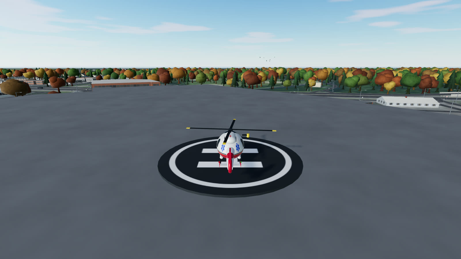 A red and white rescue helicopter on its helipad, autumn trees behind